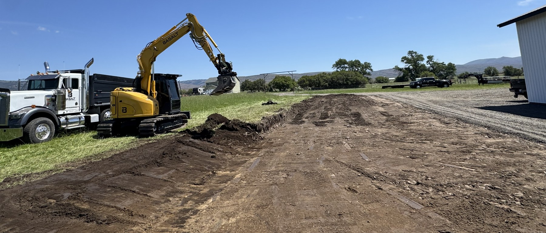 Basalt excavator and dump truck cutting a new access road on an open Central Washington site