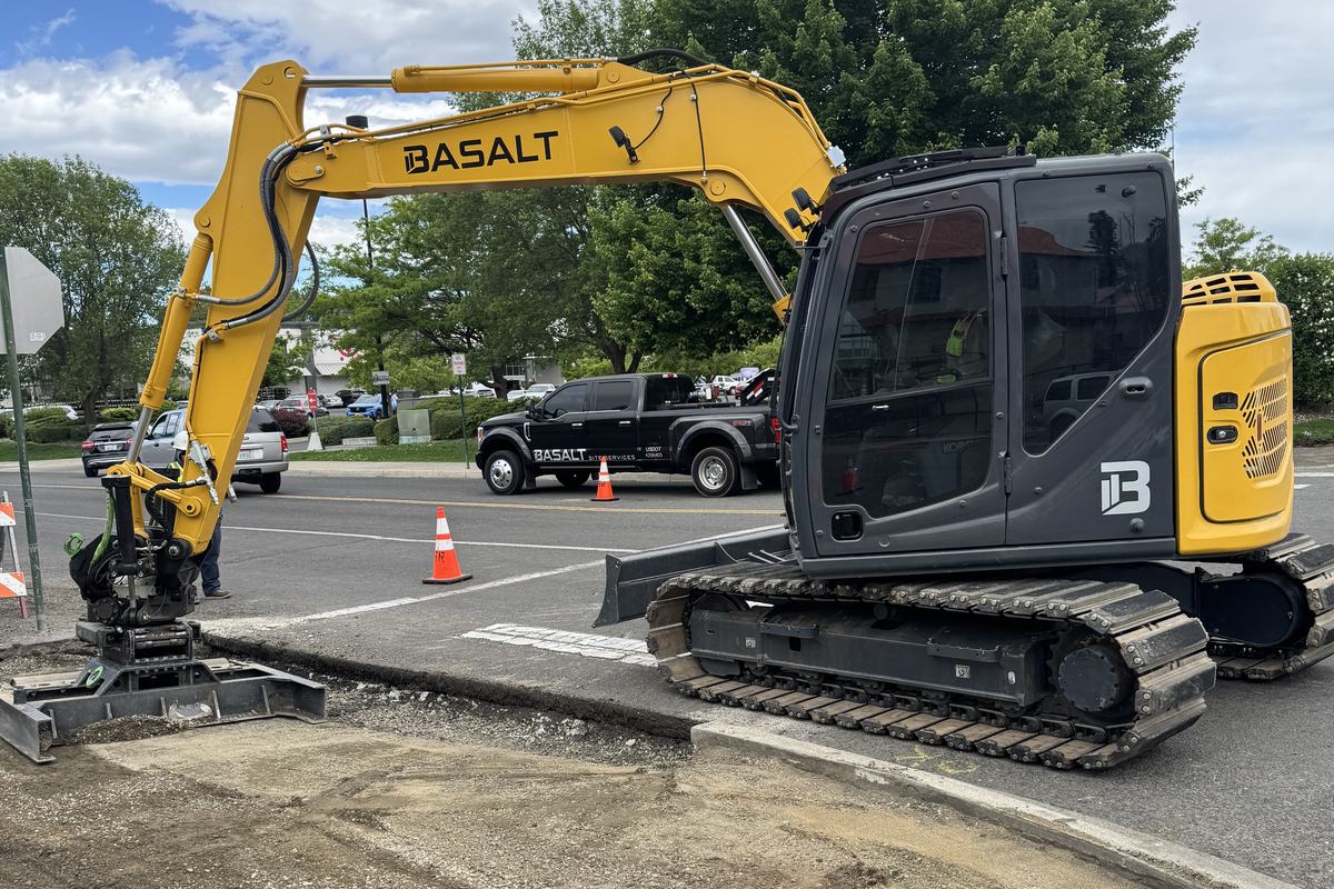 Basalt excavator with tiltrotator at a street corner with the curb removed